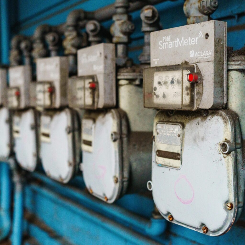 Multiple smart utility meters lined up on a blue industrial wall.
